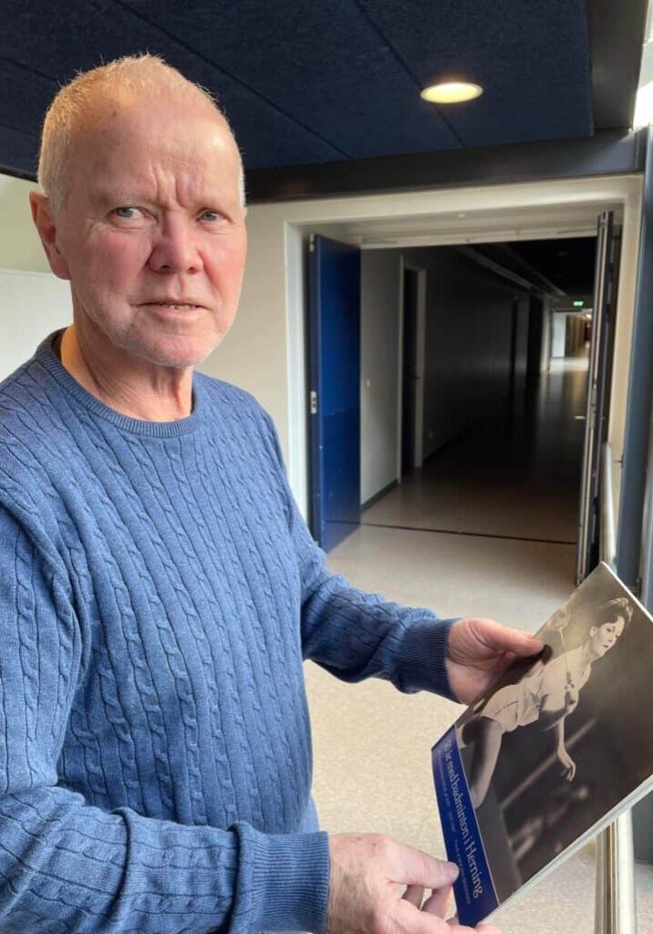 Lars Engelbrechtsen med Herning Badmintonklubs 50 års jubilæums skrift, hvor forsiden prydes af Lise Lotte Gøtsche, der vandt EM-titlen i damedouble for juniorer i 1975 sammen med Lilli B. Pedersen, Aarhus Badmintonklub.